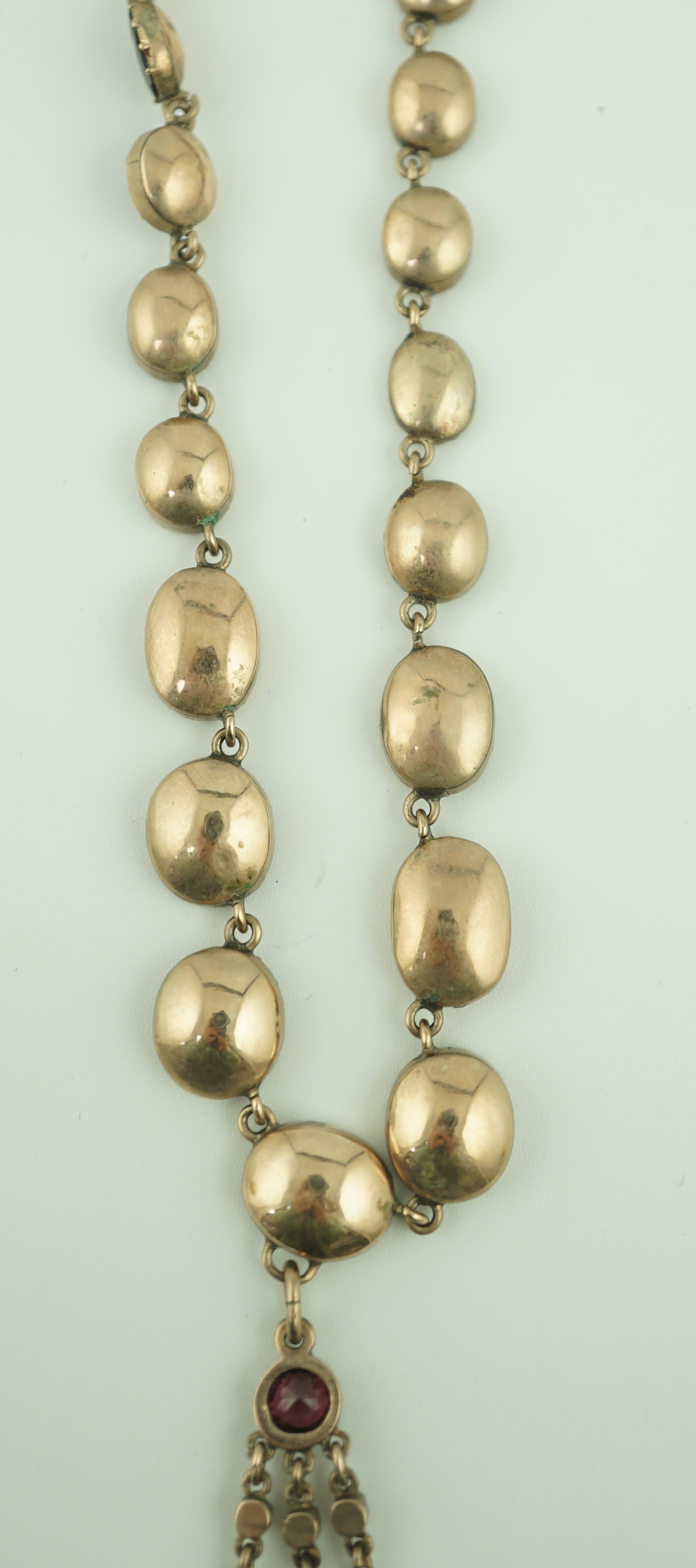 An early 19th century gold, and thirty five graduated foil backed garnet set necklace, with later garnet and seed pearl set drop